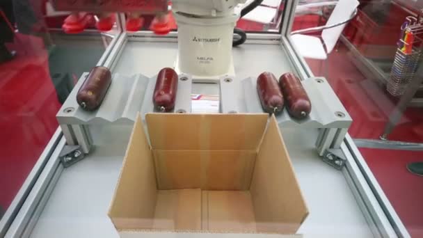 Робот кладет колбасу в коробки в AgroProdMash . — стоковое видео