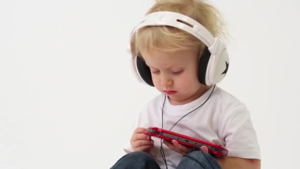 Niño pequeño con auriculares jugando juego — Vídeo de stock