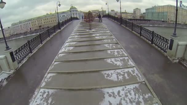 Люди ходят по мосту через реку — стоковое видео
