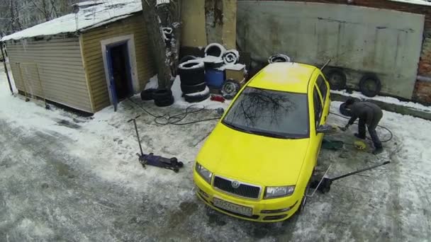 Εργαζόμενος αλλάζει τροχό του κίτρινου αυτοκινήτου — Αρχείο Βίντεο