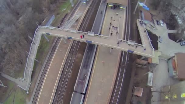 People walk by footbridge while train departs — Stock Video