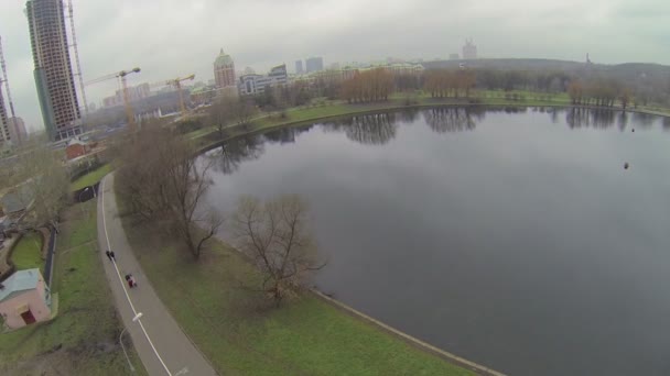 Ludzie chodzą w pobliżu staw i plac budowy — Wideo stockowe