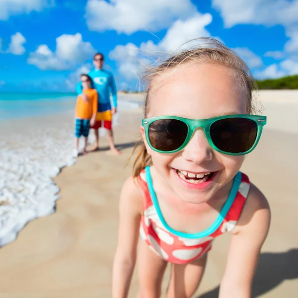 Liten flicka och hennes familj på stranden — Stockfoto