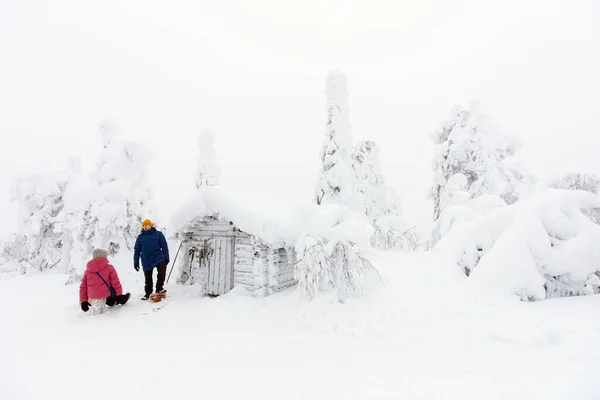 在芬兰拉普兰美丽的冬季森林里徒步旅行时 父女一家人在白雪覆盖的茅屋旁边休息 — 图库照片