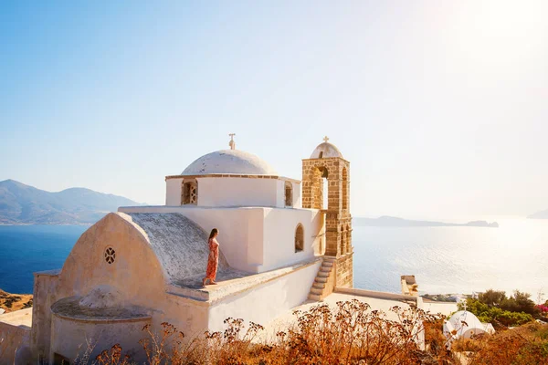 ミロス島プラカ村の伝統的な白塗りのギリシャ正教会の上から息をのむような夕日の景色を楽しむ若い女の子 — ストック写真