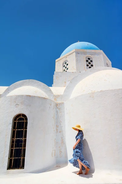ギリシャのサントリーニ島にあるピルゴス村の青いドーム型の教会の近くを歩く美しい若い女性 — ストック写真