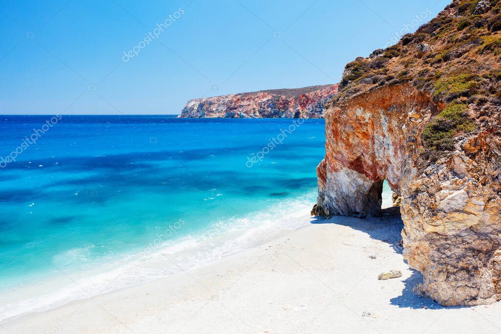 Idyllic beach surrounded by beautiful cliffs dotted with sea caves on Greek island of Milos
