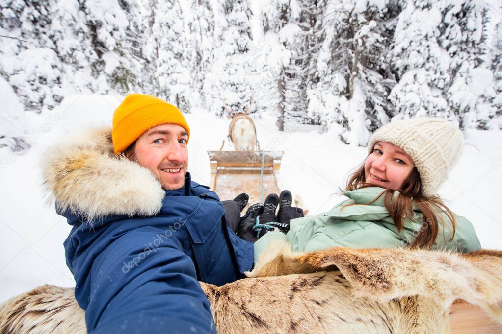 Happy couple on reindeer safari in winter forest in Lapland Finland