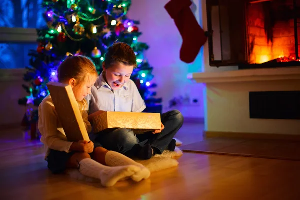 孩子们在家里打开礼物的圣诞前夜 — 图库照片