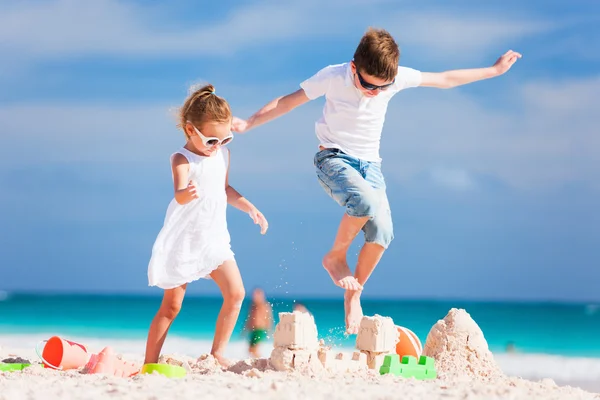 Twee kinderen verpletterende sandcastle — Stockfoto