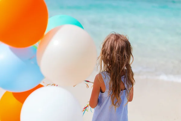 Vista trasera de niña con globos en la playa — Foto de Stock
