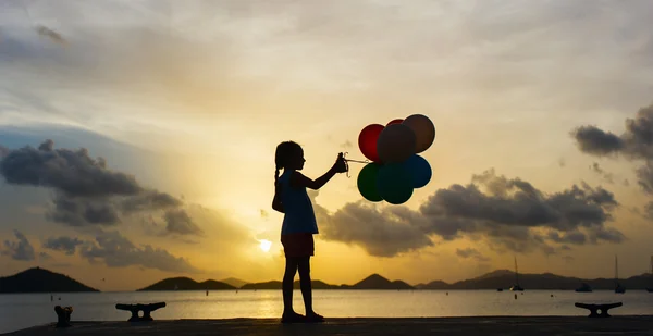 Glad tjej med ballonger i solnedgången — Stockfoto