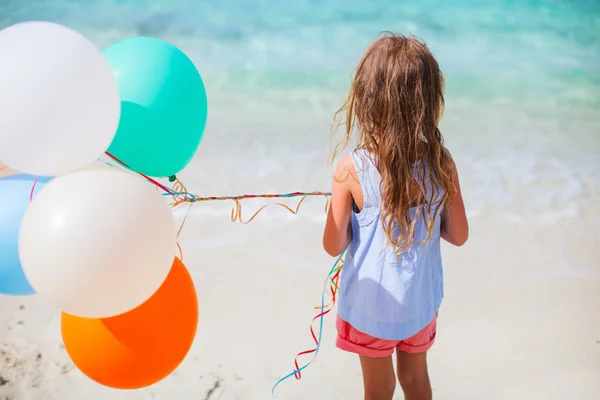 Visão traseira da menina com balões na praia — Fotografia de Stock