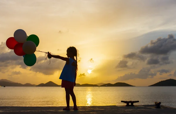 Menina feliz com balões ao pôr do sol — Fotografia de Stock