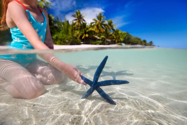 Petite fille jouant avec des étoiles de mer — Photo