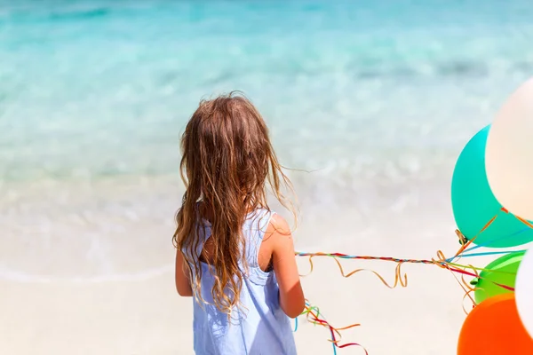 Вид сзади на девочку с воздушными шарами на пляже — стоковое фото