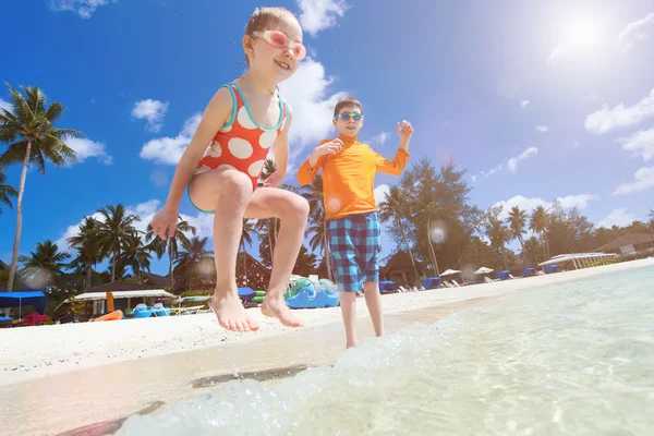 Tropical beach with kids splashing on foreground — Stock Photo, Image