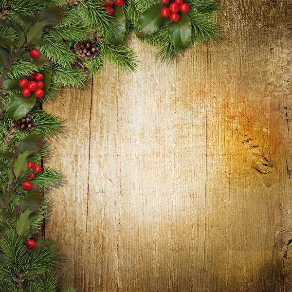 Christmas fir branches and holly on wood — Stock Photo, Image