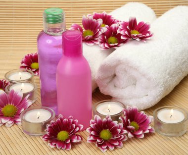 Beyaz pamuk havlu, şampuan ve gül çiçekleri.