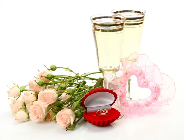 Glazen van champagne, rozen, trouwringen en hart — Stockfoto