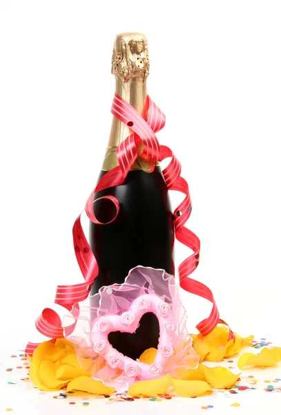 Champagne con petali di rose e cuore decorativo — Foto Stock