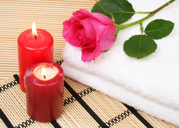 Rose auf Handtüchern mit brennenden Kerzen — Stockfoto
