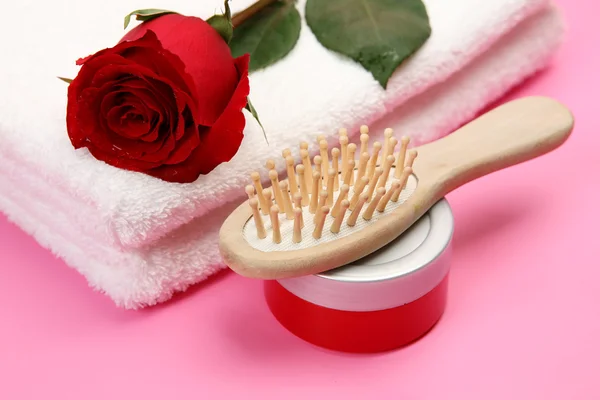 Asciugamani con rosa, bottiglia cosmetica e pettine — Foto Stock