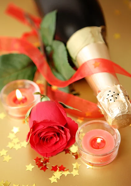Champanhe, rosa vermelha, velas acesas e fita — Fotografia de Stock