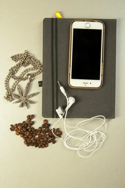 notebook, phone, headphones, necklace and coffee seeds