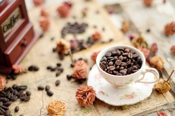 Koffiebonen en gedroogde rozen verspreid op de oude kaart — Stockfoto