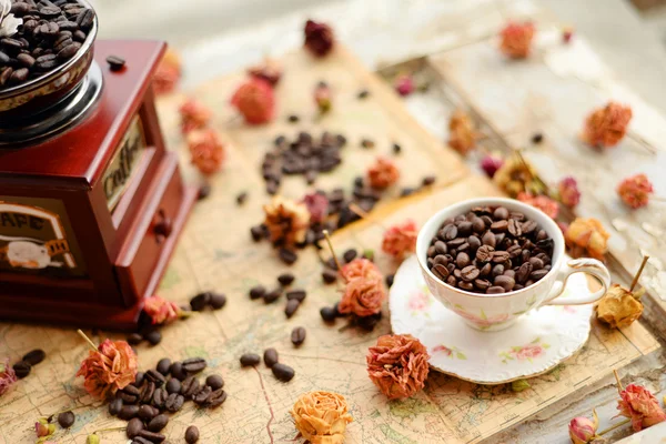 Kaffeebohnen und getrocknete Rosen auf der alten Landkarte verstreut — Stockfoto