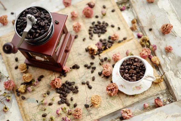 Kaffeebohnen und getrocknete Rosen auf der alten Landkarte verstreut Stockbild