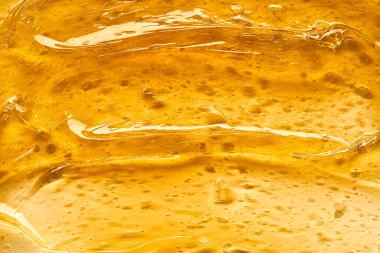 Beyaz arka planda şeffaf sarı yüz kremi ya da altın bal lekesi. Beyaz arkaplanda altın kremalı doku.