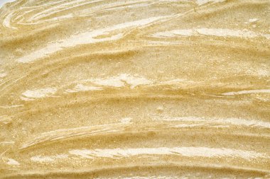 Beyaz arka planda altın kozmetik jelin şeffaf lekesi ve dokusu.