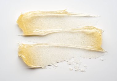 Beyaz arka planda altın kozmetik jelin şeffaf lekesi ve dokusu.