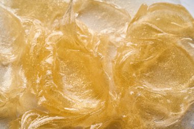 Beyaz arka planda altın kozmetik jelin şeffaf lekesi ve dokusu.