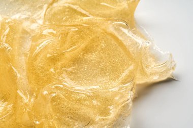 Beyaz arka planda altın kozmetik jelin şeffaf lekesi ve dokusu.