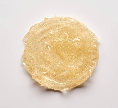 Beyaz arka planda altın kozmetik jelin şeffaf lekesi ve dokusu.