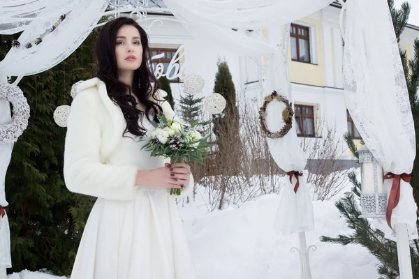 Belle mariée en cape de fourrure avec un bouquet — Photo