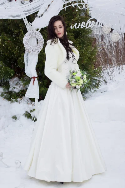 Schöne Braut in einem Pelzumhang mit einem Strauß — Stockfoto