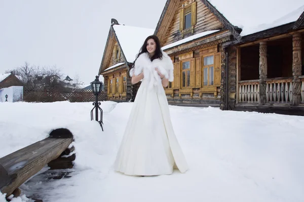 A noiva em uma capa de pele na aldeia nevada de inverno — Fotografia de Stock