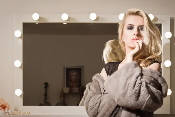 Beautiful woman in a fur near a mirror — Stock Photo, Image