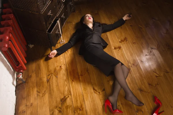 Woman in a black suit with gun lying on the floor — Stock Photo, Image