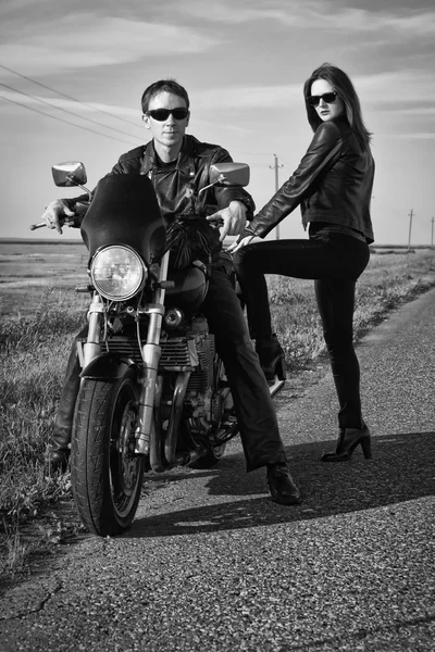 Байкер и девушка стоят на дороге — стоковое фото