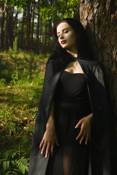 Mooie brunette vrouw in zwarte jurk en zwarte mantel in de m — Stockfoto