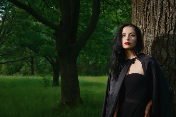 Mulher morena bonita em vestido preto e capa preta no m — Fotografia de Stock