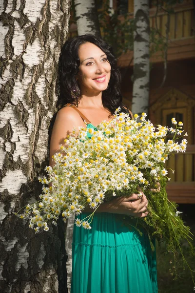 Vackra vuxen kvinna med en bukett av fältet prästkragar. — Stockfoto