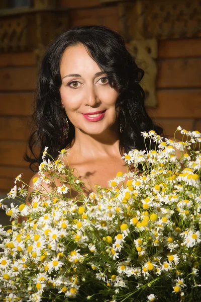 Belle femme adulte avec un bouquet de marguerites de champ . — Photo