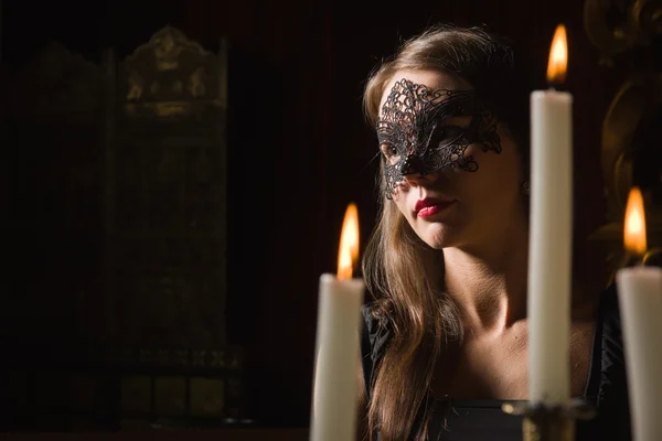 Moda sexy morena mujer con vestido negro y máscara en el dormitorio —  Fotos de Stock