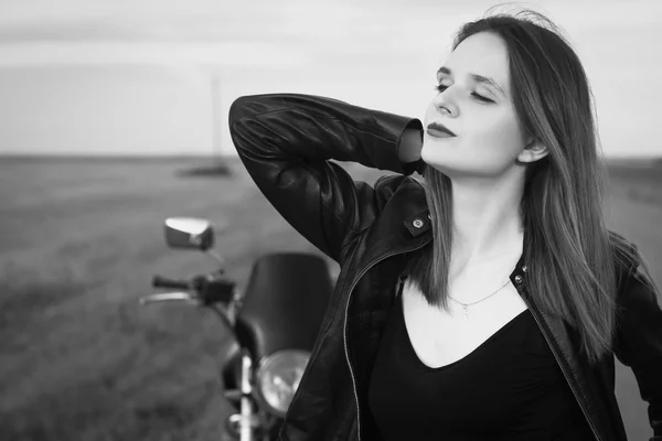 Chica motorista en una chaqueta de cuero posando cerca de la motocicleta —  Fotos de Stock